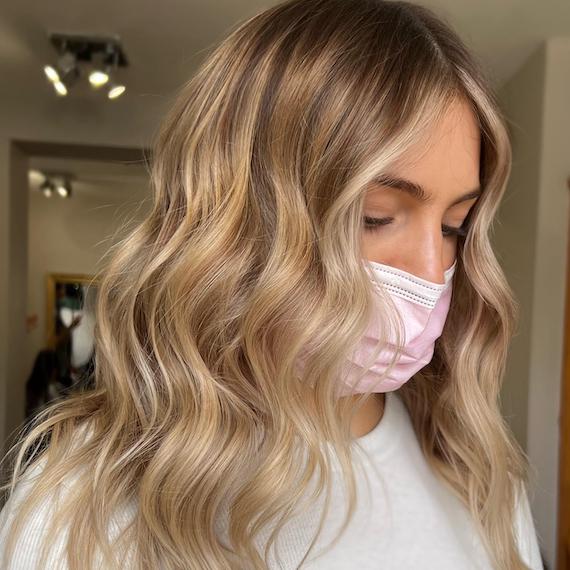 Woman gazes downwards to show off wavy, beachy blonde hair.