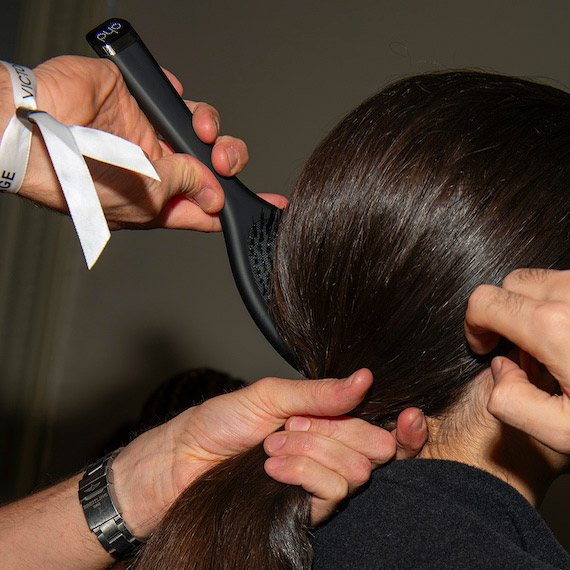 A model’s dark brown hair is brushed into a low ponytail.