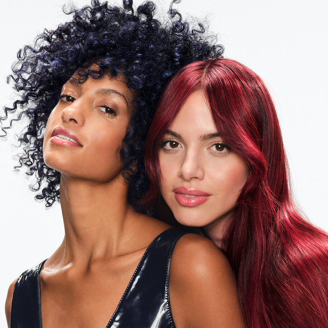 Two models posing side by side, one with dark blue hair and one with bright red hair.