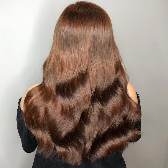 Back of woman’s head with long, wavy, brown hair, glossed using Wella Professionals