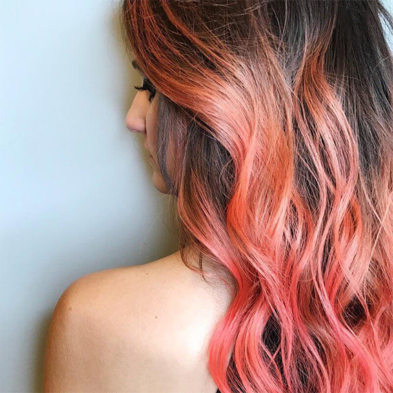 Woman with bright orange red ranbow hair, styled with loose waves