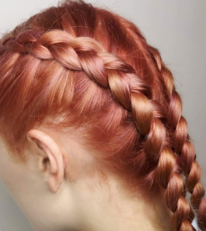 Model with peach hair styled  into two braids, created with Blondor and Koleston Perfect