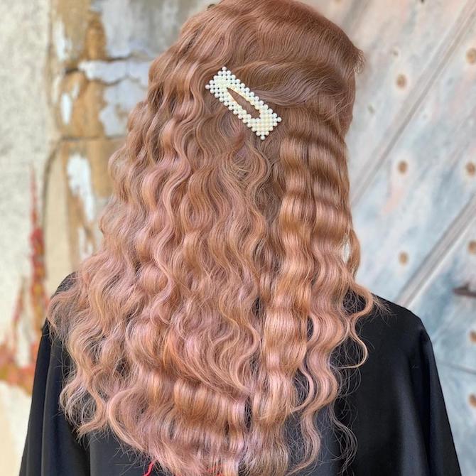 Back of a woman’s hair with tight waves and a pearl barrette, created using Wella Professionals.