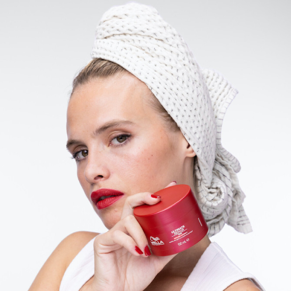 Model with wet hair wrapped in a towel holds up ULTIMATE REPAIR Mask.