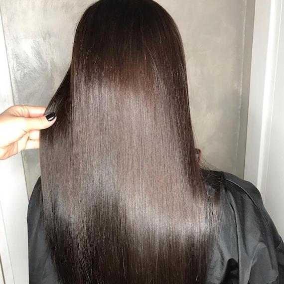 Back of woman’s head with long, silky-straight, dark brunette hair, created using Wella Professionals. 