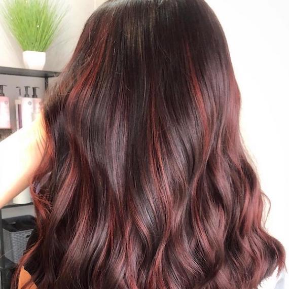 Back of woman’s head with long, wavy, cherry chocolate hair, created using Wella Professionals.