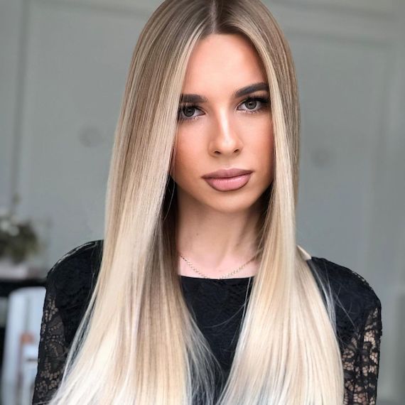 Model with long, bright, ash blonde ombre hair faces the camera.