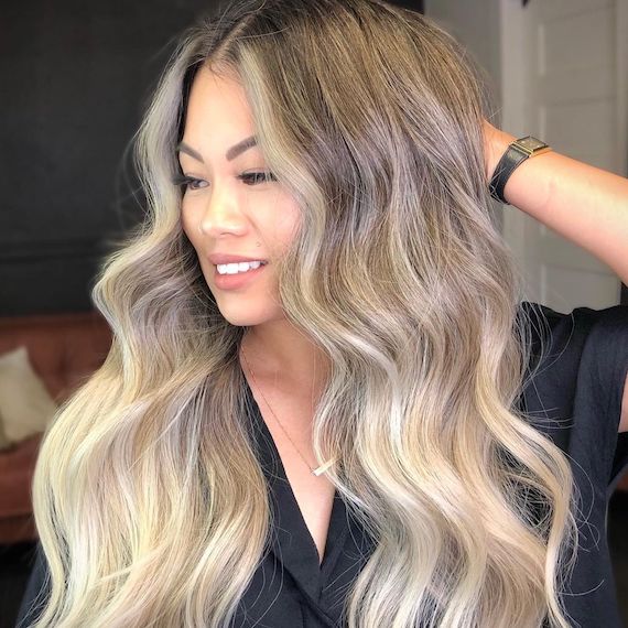 Model with light and bright, long, ash blonde ombre hair gazes to the side.