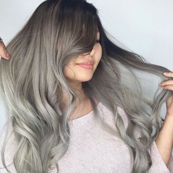 Model with long, loosely curled, gray and ash blonde ombre hair.