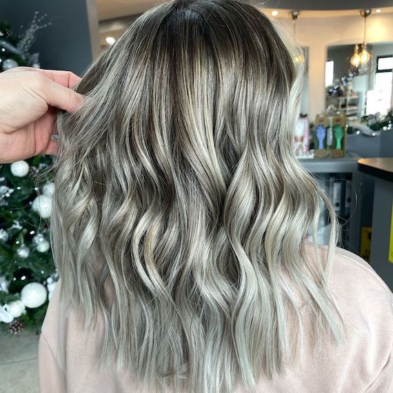 Back of woman’s head with mid-length, wavy, blonde and ash green hair