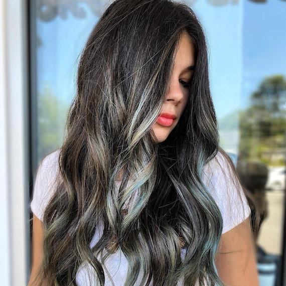 Woman with long, wavy, dark brunette hair and ashy aqua highlights