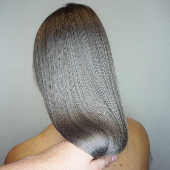 back of woman’s head with sleek, straight hair dyed silver ash gray 