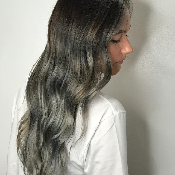 woman with long, wavy hair in ash gray balayage