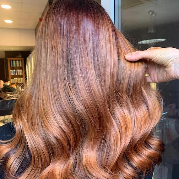 Back of woman’s head with long, glossy, auburn strawberry blonde hair. 