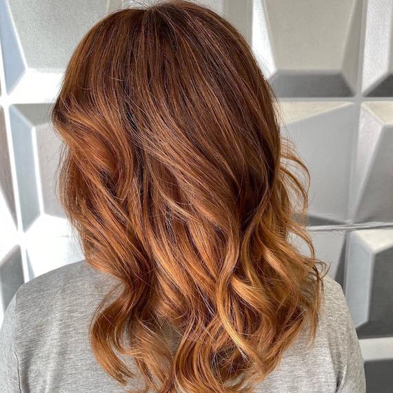 Back of woman’s head with mid-length, light auburn hair and blonde highlights. 