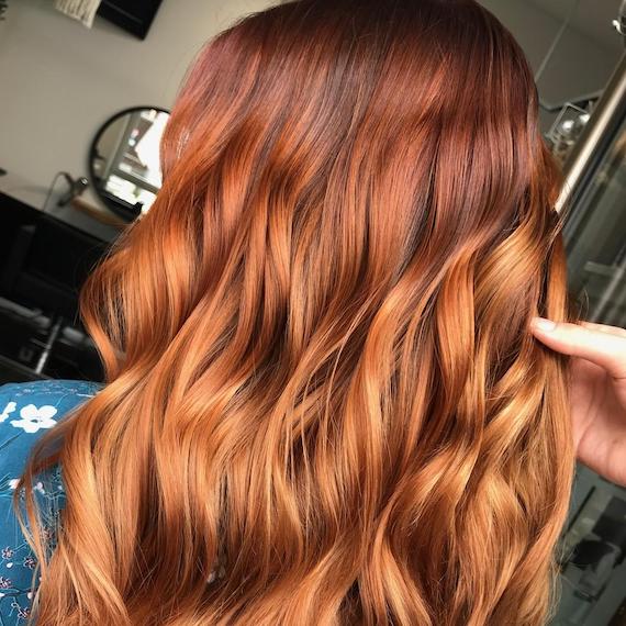 Back of woman’s head with tousled, medium auburn hair and blonde highlights. 