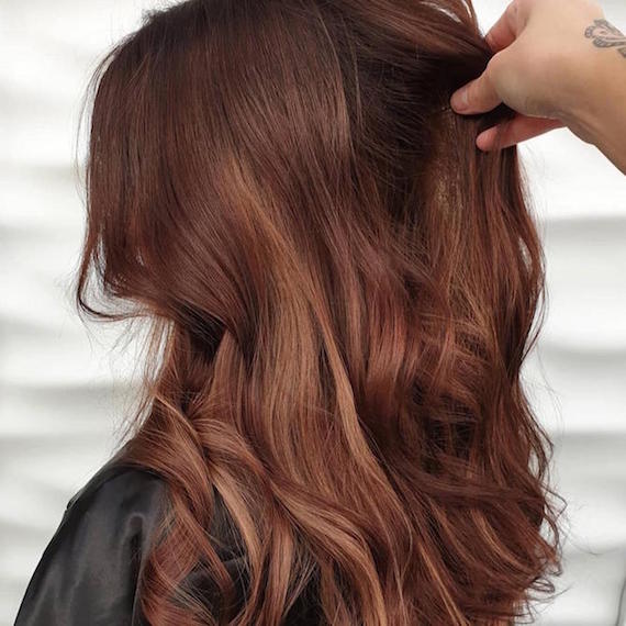 Side profile of woman with true auburn hair color, created using Wella Professionals.