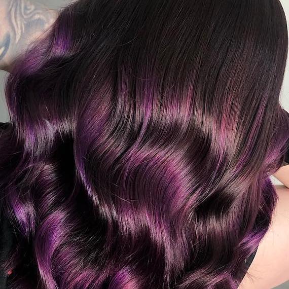 Back of woman’s head with long, wavy, dark purple hair, created using Wella Professionals.