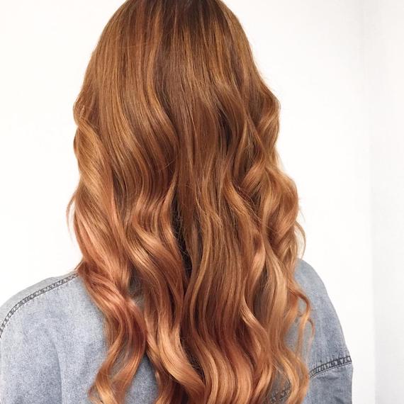 Back of a woman’s head with long, wavy strawberry blonde hair and babylights, created using Wella Professionals.