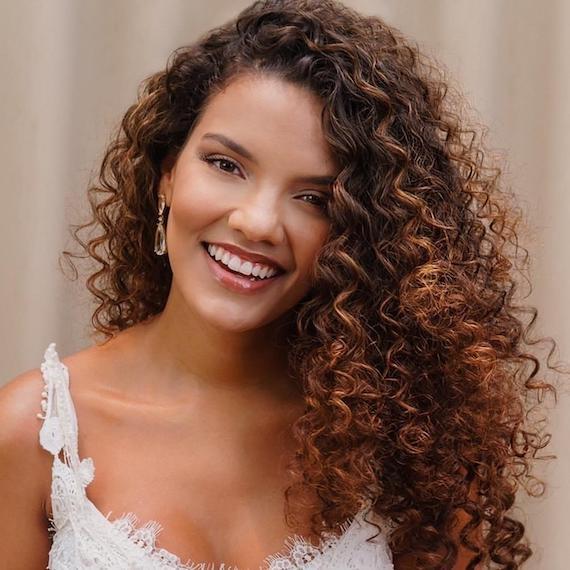 Young brunette woman with tanned skin and curly hair in white