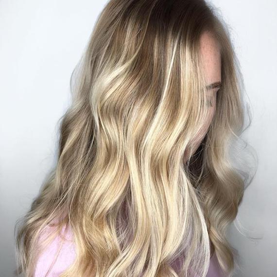 Model with long, wavy hair and blonde balayage, created using Wella Professionals. 