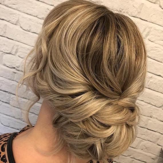 Back of woman’s head with blonde, balayaged chignon, created using Wella Professionals.