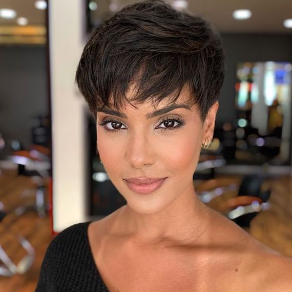 Model with a dark brown pixie haircut, featuring layered bangs.