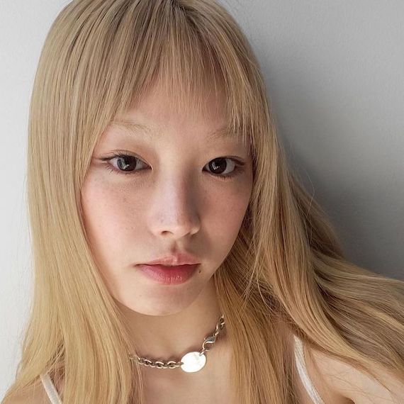 Model with long, straight, honey blonde hair and short micro bangs.