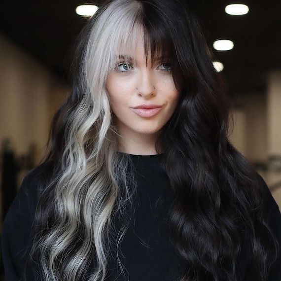 Model with long, wavy, black and white color block hair and wispy bangs.