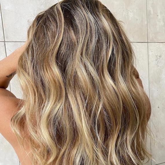 Back of woman’s head with beachy, caramel blonde wavy hair, created using Wella Professionals.