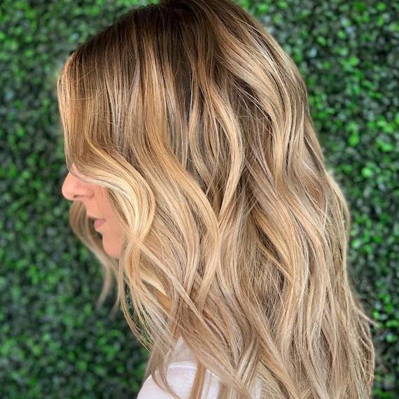 Side profile of woman with beach blonde, wavy hair, created using Wella Professionals.