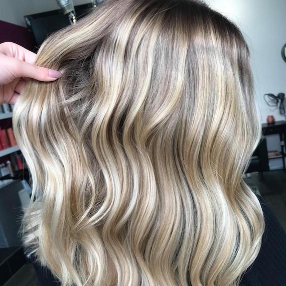 Seitenprofil einer Frau mit gewelltem, beige-blondem Haar, erstellt mit Wella Professionals.