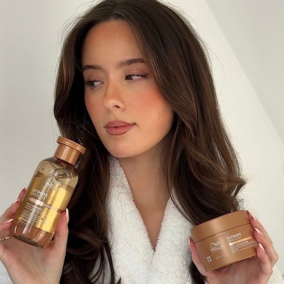 Model with long, brown hair holding ULTIMATE SMOOTH Shampoo and ULTIMATE SMOOTH Mask.