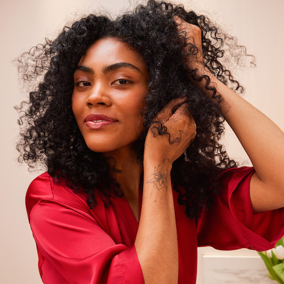 Model smooths ULTIMATE REPAIR Night Serum through dark, curly hair.