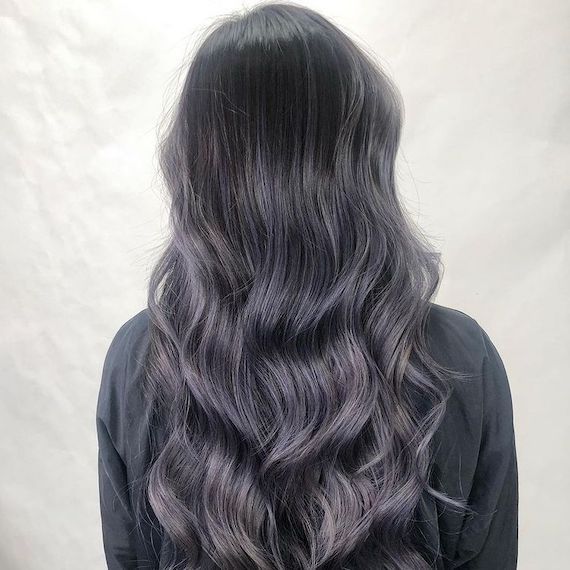 Back of model’s head with long, loosely curled, black hair and silver lavender balayage.