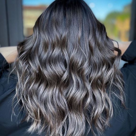 Back of model’s head with long, black, tousled hair and silver blonde highlights.