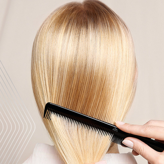 Back of woman’s head as her straight blonde hair is combed.