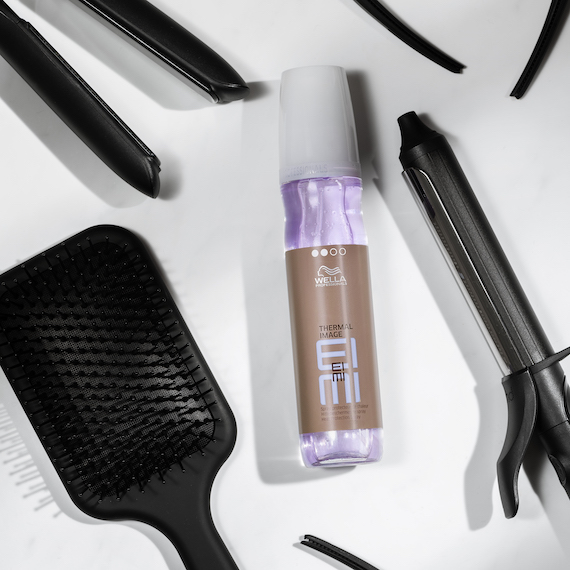 Wella EIMI Thermal Image heat protection spray on a flat surface with other hair tools.