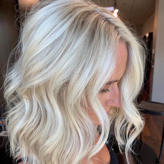 Woman with shoulder-length, wavy hair and platinum blonde balayage, created using Wella Professionals. 