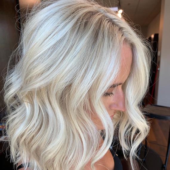 Woman with shoulder-length, wavy hair and platinum blonde balayage, created using Wella Professionals.
