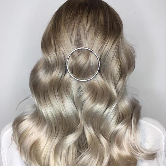 Back of woman’s head with long, loosely-curled hair and icy blonde balayage, created using Wella Professionals.