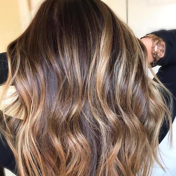 Back of woman’s head with brown to golden blonde balayage, created using Wella Professionals.