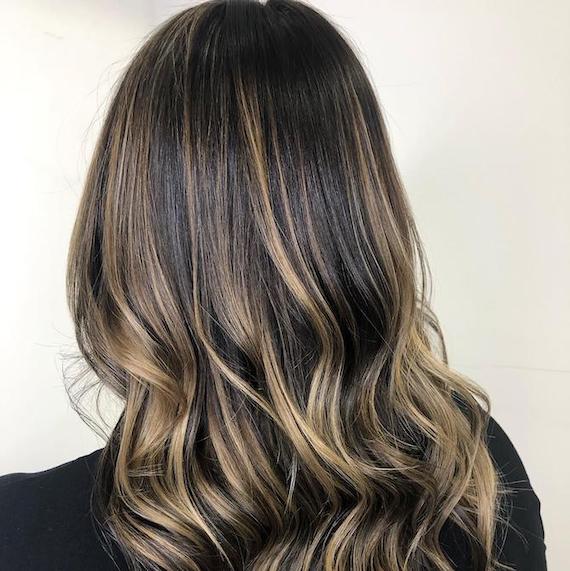 Back of woman’s head with dark brown to blonde balayage, created using Wella Professionals.