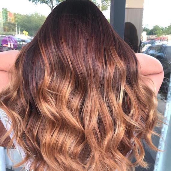 Back of woman’s head with red brown to strawberry blonde balayage, created using Wella Professionals.