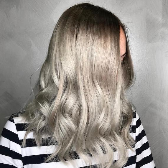 Side profile of woman with long, gray blonde hair, created using Wella Professionals.