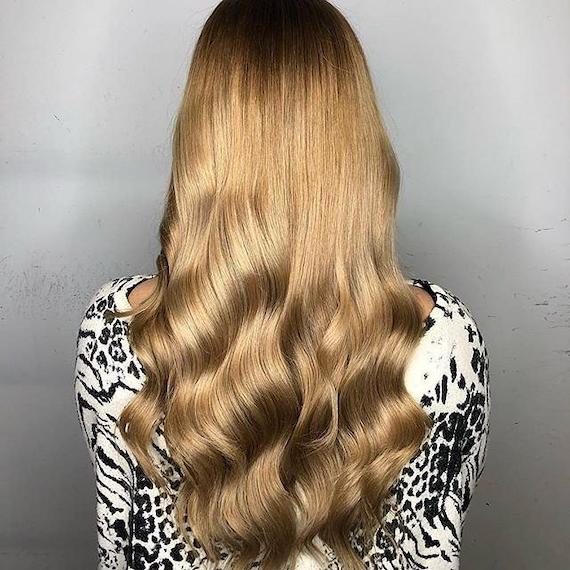 Back of woman’s head with long, loosely curled, caramel blonde hair, created using Wella Professionals.