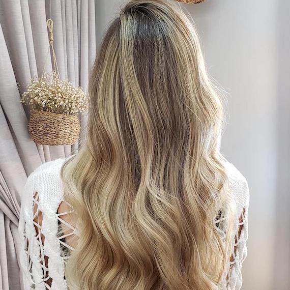 Half head of blonde highlights on long, wavy hair, created using Wella Professionals.