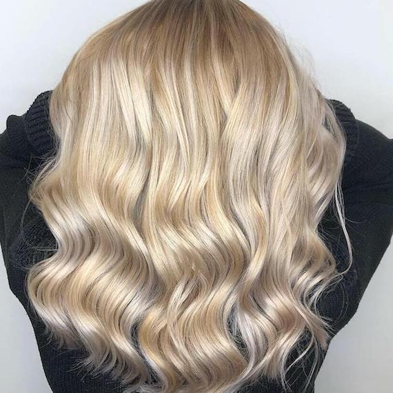 Full head of blonde highlights on long, wavy hair, created using Wella Professionals.