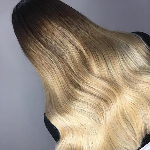 Blonde ombre highlights through long, wavy hair, created using Wella Professionals.