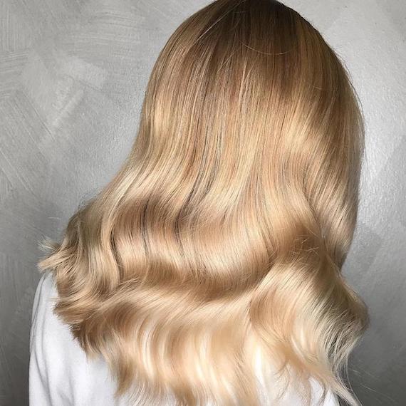 Blonde sombre highlights through long, wavy hair, created using Wella Professionals.